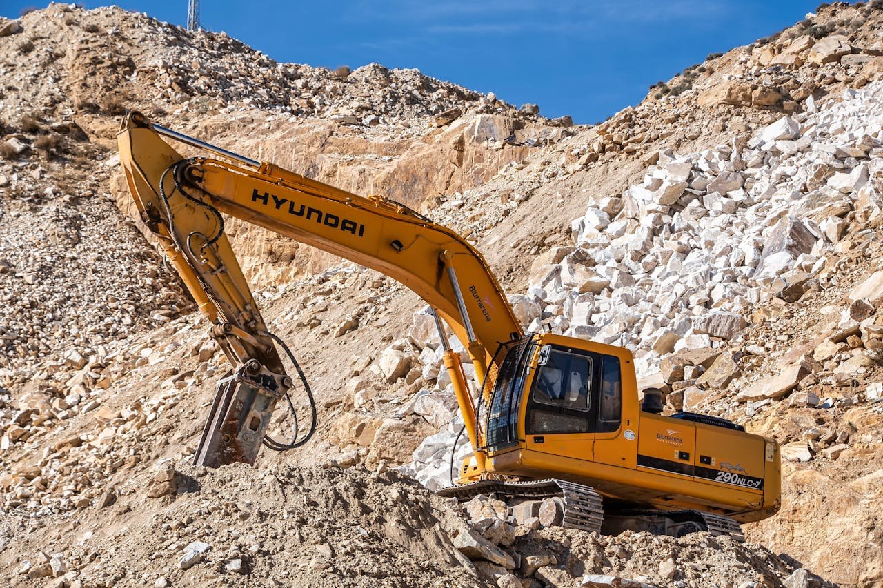 Mastering the First Impression: Your intriguing post title goes here Yellow Hyundai excavator operating in a rocky quarry under a clear blue sky. Perfect for industrial themes.